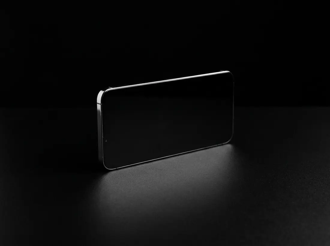 A slab of black glass standing on edge against black, one bright line along its chamfer