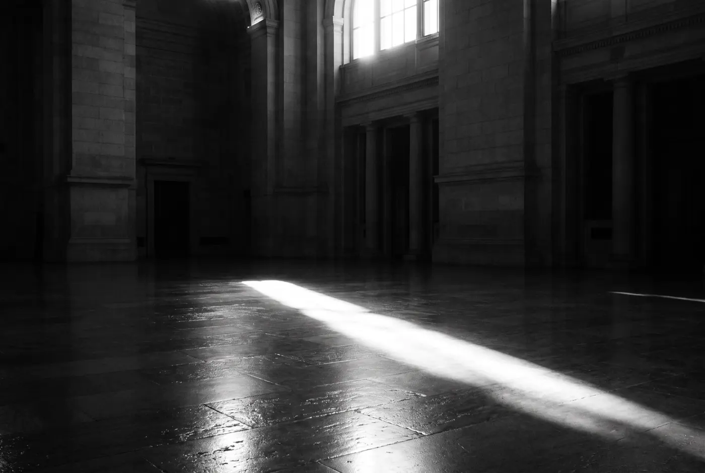 A shaft of daylight crossing the polished stone floor of a monumental government hall